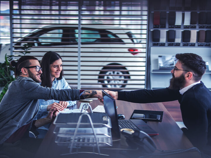 two car buyers and a dealership salesperson closing a deal