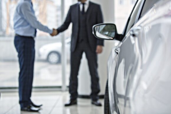 car buyer and salesperson shaking hands in a dealership showroom