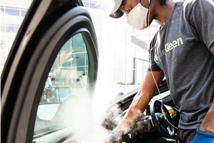 A service employee using specialized cleaning equipment to sanitize a vehicle for a test drive or after a service and repair appointment