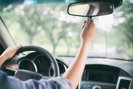 Woman adjusting the rear view mirror of a car