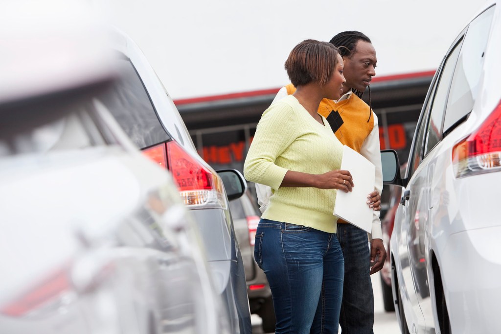 Couple shopping for pre-owned car at dealership